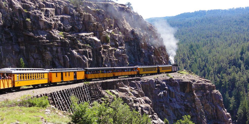 Durango and Silverton Railroad steaming along side mountain side.