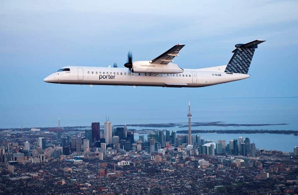 Porter Airlines aircraft flying with the Toronto skyline in the background.