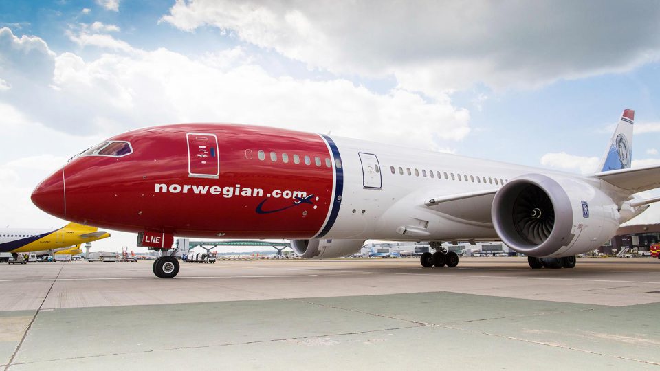 Red and white Norwegian Boeing Dreamliner at airport.