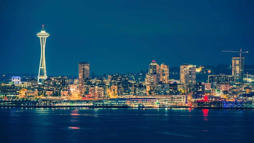 Colorful Seattle skyline reflects on the water at night.