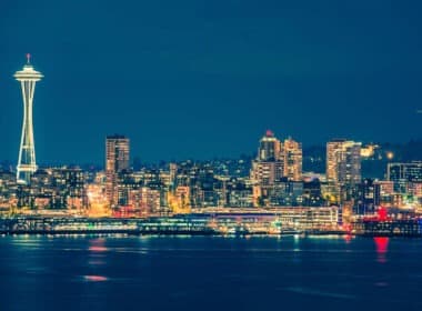 Colorful Seattle skyline reflects on the water at night.