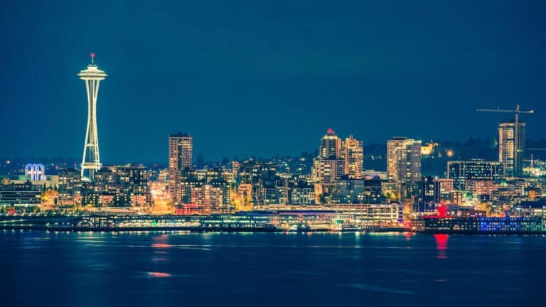 Colorful Seattle skyline reflects on the water at night.